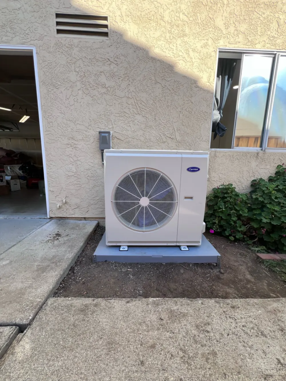 Carrier heat pump condenser installed beside the garage of a Union City home