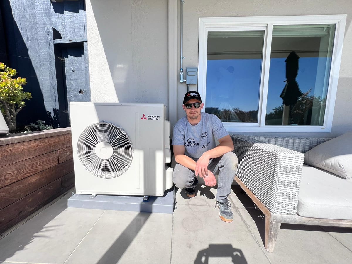 Galaxy Heating & Air technician with a newly installed Mitsubishi ductless heat pump outdoor unit at a Victoria by the Bay Hercules home