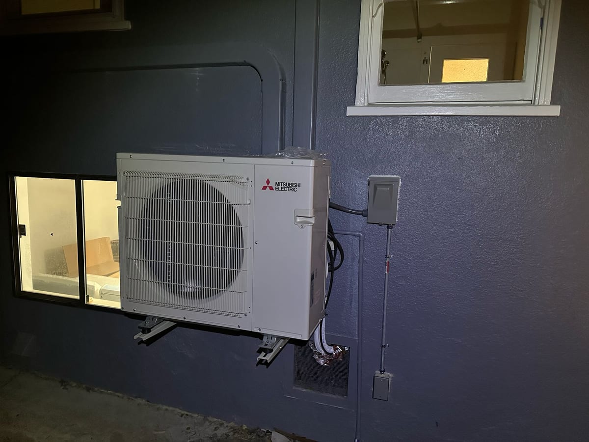 Mitsubishi Electric ductless heat pump outdoor unit on wall-mounted bracket installed by Galaxy Heating & Air at an Allied Arts Menlo Park home