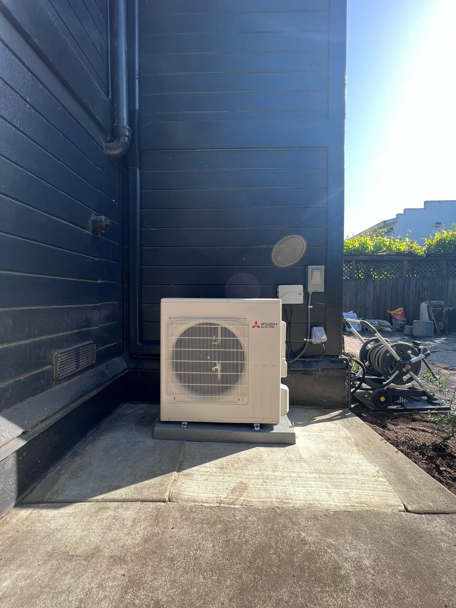 Mitsubishi ductless heat pump outdoor unit installed by Galaxy Heating & Air at a Piedmont Hills home with classic dark board siding